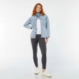 Sobrecamisa de denim celeste con cuello clásico, cierre frontal con botones a presión, mangas largas con puños abotonados, dos bolsillos de parche en el pecho y corte holgado.