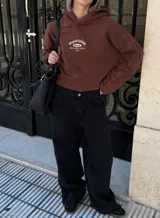 Pantalón de jean negro de tiro alto y corte palazzo, con cinto de cuero negro con hebilla plateada. Blusa de encaje negra con mangas acampanadas.