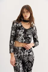 Blazer negro de terciopelo con estampado floral plateado, corte cropped y mangas largas.
