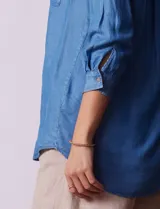 Blusa celeste de lyocell, con cuello con solapa, escote en V y abertura con botones. Mangas ¾ con puño y botón.