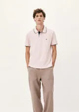 Camisa polo color rosa claro con cuello clásico, tapeta de dos botones y bordado de logo en el pecho. Presenta ribete azul marino en cuello y mangas. Corte clásico.
