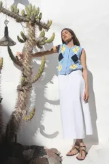 Chaleco celeste de punto con patrón de rombos en amarillo y negro, cuello redondo y cierre frontal con botones dorados.