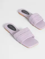 Sandalias bajas color beige con tira ancha acolchada.