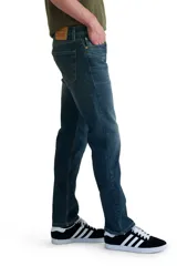 Jeans de corte slim fit, color azul oscuro con desgaste en muslos y rodillas.