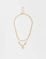 Collar corto triple dorado con cadenas de diferentes grosores. La cadena inferior tiene cuentas de colores y un dije redondo con diseño de sol.