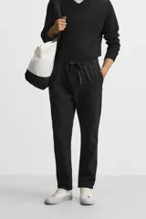 Pantalón de jogging color beige confeccionado en tejido de mezcla de algodón. Cuenta con cintura elástica ajustable con cordón, bolsillos frontales y traseros.