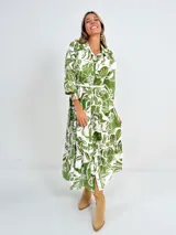 Vestido largo camisero con estampado floral en tonos rosados y blancos, con cuello camisero, manga 3/4 y falda escalonada. Incluye cinturón fino de soga.