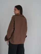 Camisa gris de lana con corte clásico, cuello camisero, cierre frontal con botones de cuerno y dos bolsillos de parche en el pecho.