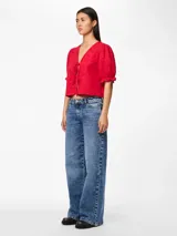 Blusa roja con estampado floral, escote en V con lazos, mangas cortas abullonadas con volantes en los puños y corte cropped.