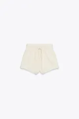 Shorts color crudo de tiro medio con cintura elástica ajustable con cordones y bajo desflecado.