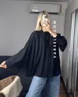 Camisa blanca de mangas largas con detalles de encaje en el cuello y en el frente.