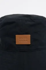 Gorro tipo bucket negro de tejido gabardina con etiqueta de piel logotipada.