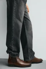 Bota estilo Chelsea de cuero negro, con punta fina, elásticos laterales y tirador trasero. Posee suela con ligero tacón.