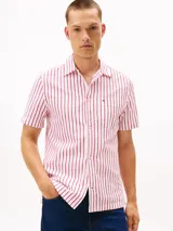 Camisa de manga corta confeccionada en tejido seersucker de algodón BCI a rayas rojas y blancas. Tiene cuello clásico, cierre con botones y logo de Tommy Hilfiger bordado en el pecho.