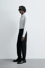 Camisa de algodón color celeste claro, corte regular fit, con cuello abotonado (button-down), manga larga con puño abotonado y bolsillo de parche en el pecho izquierdo.