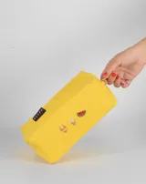 Neceser naranja de tela con cierre superior y logo de la marca en etiqueta negra. Presenta bordados de emojis: copa de vino, fuegos artificiales y mano verde.