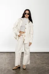 Pantalón wide leg de lino y algodón color crudo con rayas verticales finas color rosa. Tiene tiro medio, cartera cruzada con botones carey y bolsillos laterales.