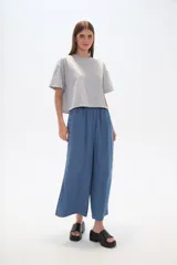 Pantalón capri de denim azul con cintura elástica y aberturas laterales en el ruedo.