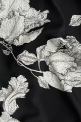 Pantalón de sarga suave con estampado floral en blanco y negro, tiro alto, cintura elástica con cordón ajustable, piernas rectas con puño en el bajo y detalle de doble línea blanca en el ruedo.