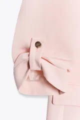 Blazer color marrón oscuro, de corte recto, con cuello solapa y hombreras. Tiene mangas 3/4 con trabilla y botón dorado, y bolsillos delanteros con solapa.