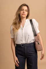 Bandolera pequeña de textura símil cuero color caramelo/marrón, con dos compartimentos principales con cierre. Correa ancha ajustable de tela negra con inscripción en relieve.