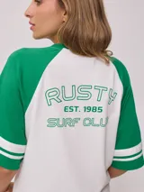 Remera bicolor Rusty con cuerpo verde lima y mangas ranglán grises con dos rayas blancas en los puños. Estampado frontal con el logo de la marca y el número 85.