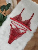Conjunto de lencería de encaje rojo compuesto por el Bra Olimpia, un corpiño tipo bralette triangular con breteles finos, y la Tanga Bosque, una bombacha tipo tanga con detalles de tiras elásticas decorativas en la cintura.