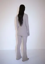 Conjunto de jersey y pantalón de punto acanalado color gris topo. El jersey es de cuello alto con cremallera, manga larga acampanada y corte entallado.