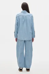 Camisa de jean color crudo, corte oversized, con botones rojos y pespuntes a contratono.