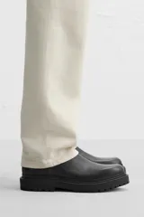 Bota Chelsea de cuero negro con elásticos laterales, tirador trasero y suela track.