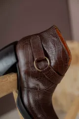 Botas cortas de cuero negro con textura tipo cocodrilo, caña alta, cierre con hebilla y taco de madera.