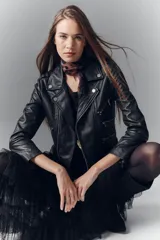 Campera negra de cuero ovino, estilo rocker, con cinturón, charreteras y solapas. Tiene cierres y detalles metálicos en frente y espalda.