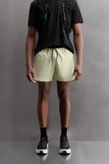 Shorts deportivos color verde oliva confeccionados en tejido técnico ligero y elástico. Cuenta con forro interior, cintura elástica ajustable con cordón, bolsillos laterales, bolsillo de seguridad en espalda con cierre de cremallera, bajo con aberturas laterales y logo estampado en la pierna.