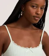 Top de bretel fino color blanco roto, confeccionado en tejido acanalado, con ribete de encaje y un pequeño moño decorativo en el centro del escote.