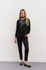 Pantalón babucha negro de calce relajado, con elástico y cordón ajustable en la cintura, bolsillos diagonales en el frente y falsos bolsillos ojal en la espalda.