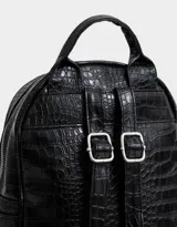 Mochila negra con efecto piel de cocodrilo, bolsillo frontal con cierre, charm de monedero colgante, correas regulables, manija superior, doble cierre superior y bolsillos laterales.