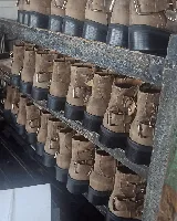 Bota corta de cuero vacuno color marrón claro, con hebillas metálicas y suela de goma negra.