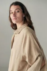 Vestido largo color beige de lino, con cuello camisero, media cartera con un botón, mangas 3/4 con tajos y bolsillos laterales.