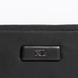 Billetera negra con cierre de cremallera y logo metálico de la marca en el centro.