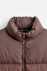 Campera puffer marrón con cuello alto, cierre frontal con cremallera, bolsillos laterales y puños elásticos.