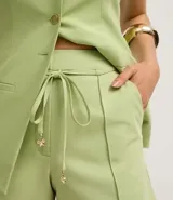 Short de vestir de tiro alto, corte recto, color verde claro, con amarre en la cintura y nervaduras frontales.