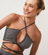 Blusa cropped de punto plateada con escote halter, tirantes finos cruzados en el pecho y la nuca, y lazo en la cintura.