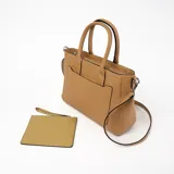 Cartera tipo tote de cuero sintético color marrón, con doble asa corta y correa larga extraíble. Tiene un bolsillo frontal con cierre y herrajes plateados.
