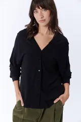 Blusa negra de manga larga con escote en V y cierre frontal con botones.