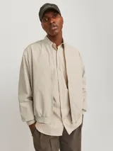 Campera bomber color beige de Jack & Jones, con cuello baseball, cierre frontal con cremallera, bolsillos delanteros y puños de canalé.