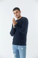 Sweater azul marino de punto con cuello redondo y logo bordado en el pecho.