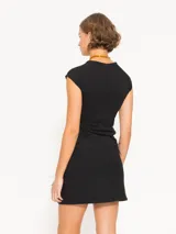 Top negro de tejido de punto con cuello redondo y mangas cortas estilo raglán. Presenta plumas aplicadas en el frente y logo bordado en la espalda.