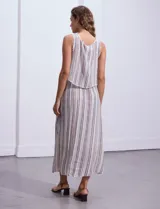 Vestido largo sin mangas, con estampado a rayas verticales en tonos beige, marrón y blanco. Tiene escote redondo y corte a la cintura con punto smock.
