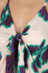 Vestido playero estampado con flores moradas y verdes, breteles finos y volados en el frente.