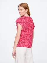 Blusa blanca de manga corta con escote en V y detalle de volados en el cuello.